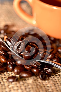 Coffee cup with burlap sack of roasted beans on rustic table