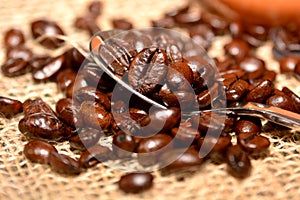 Coffee cup with burlap sack of roasted beans on rustic table