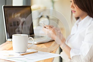 Coffee cup and Businesswoman working with documents and laptop