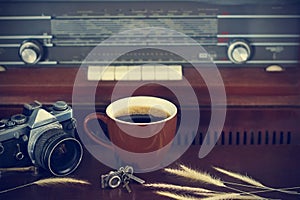 Coffee cup and camera film on retro radio background