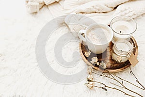 Coffee cup with candles in cozy home atmosphere. Warm sweater