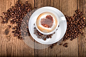 Coffee cup Cappuccino on old wooden table. Heart shape foam, top view