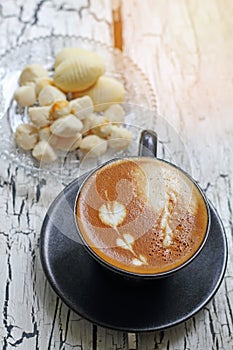 Coffee cup of cappuccino and Thai cookie with reflection from wi