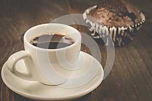 coffee cup and a chocolate muffin/coffee cup and a chocolate muffin on a dark wooden background. Selective focus