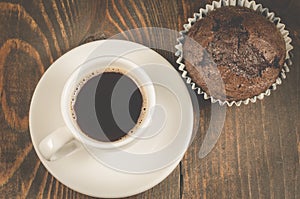 coffee cup and a chocolate muffin/coffee cup and a chocolate muffin on a dark wooden background. Top view