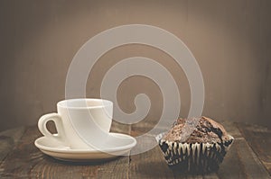 coffee cup and a chocolate muffin/coffee cup and a chocolate muffin on a dark wooden table