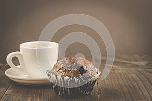 coffee cup and a chocolate muffin/coffee cup and a chocolate muffin on a dark wooden table. Copy space