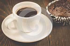 coffee cup and a chocolate muffin/coffee cup and a chocolate muffin on a wooden background, selective focus