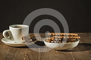 Coffee cup with cinnamon and cookies/white coffee cup with cinnamon and cookies on a wooden table. Copy space