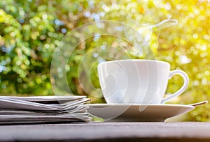 coffee cup clock and news paper on old wooden table nature background