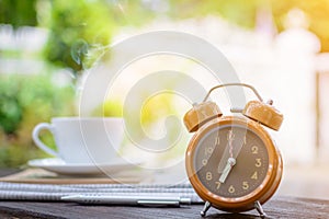 coffee cup clock and news paper on old wooden table nature background