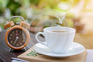 coffee cup clock and news paper on old wooden table nature background