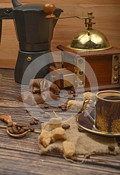 Coffee Cup, coffee beans, brown sugar, chocolate pieces, coffee maker, coffee grinder on wooden background