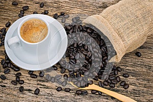 Coffee cup and coffee beans roasted in sack on a wooden floor