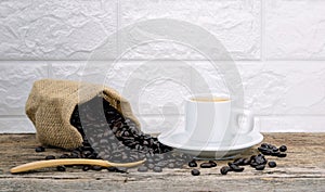 Coffee cup and coffee beans roasted in sack on a wooden floor