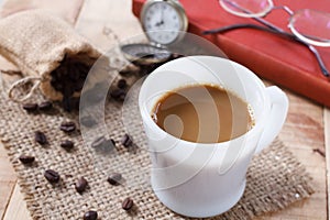 Coffee cup and coffee beans on sackcloth mat, selection focus.