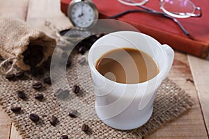 Coffee cup and coffee beans on sackcloth mat, selection focus.