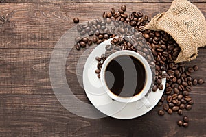 Coffee cup and coffee beans on wooden background. Top view.