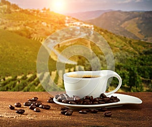 Coffee cup with Coffee beans on the wooden table and plantations