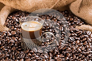 Coffee cup and coffee beans on a wooden table and sack background