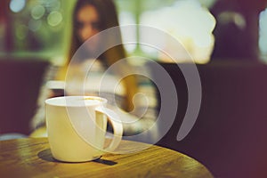 Coffee cup in coffee shop and woman with mobile phone