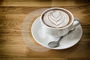 Coffee cup in coffee shop on wooden table background- vintage style effect picture