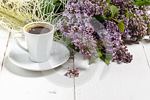 Coffee cup and colorful lilac flowers on garden table