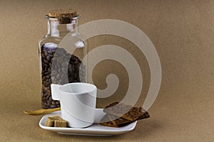 Coffee cup, cookies and a glass jar full of coffee beans.