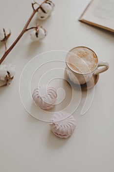 coffee cup, flower, candle and a book on a white table background top view