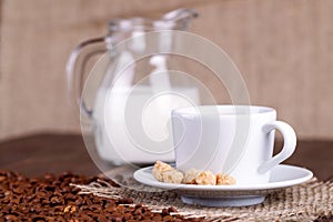 Coffee cup, cream, coffee grains and cane sugar