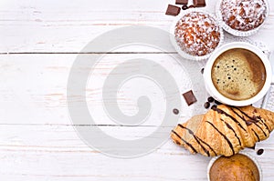 Coffee cup with a croissant and cake .