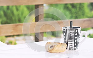 A coffee cup with a croissant on the table, a veranda of a country house, a toned photo