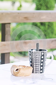 A coffee cup with a croissant on the table, a veranda of a country house, a toned photo