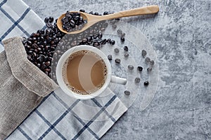 Coffee cup with Dark Roasted coffee beans in bag and wooden spoon on old kitchen table cement top