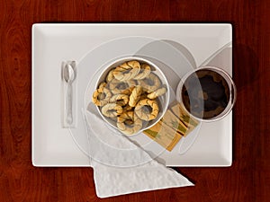 Coffee cup, double glass coffee cup with bowl of cookies, spoon, napkin and sugar sachets on white ceramic tray on wooden table