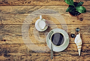 Coffee cup, flower in pot, pitcher of milk on wooden table