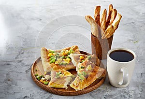 Coffee cup, freshly baked fruit pies and breadsticks on an grey textured background, close-up, selective focus.