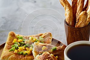 Coffee cup, freshly baked fruit pies and breadsticks on an grey textured background, close-up, selective focus.