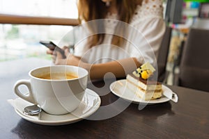 Coffee cup is in front of woman using her smart phone