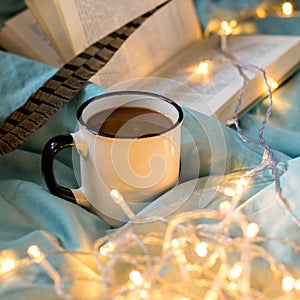 Coffee cup and garland on a bed. Atmospheric hygge style. Cozy winter or autumn concept