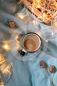 Coffee cup and garland on a bed. Atmospheric hygge style. Cozy winter or autumn concept