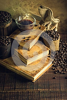 Coffee in cup glass on old books and aged wood floor