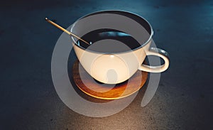 coffee cup with golden spoon and wooden saucer on concrete table