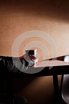 Coffee cup in hands, on the table