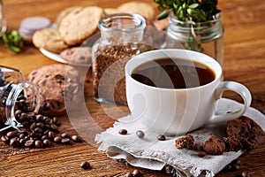 Coffee cup, jar with coffee beans, cookies over rustic background, selective focus, close-up, top view