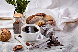 Coffee cup, jar with coffee beans, cookies on white table selective focus, close-up, top view