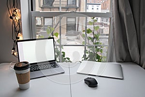 Coffee cup and laptop with blank screen on table in office