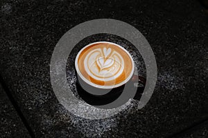 Coffee cup with latte art on the floor