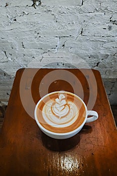 Coffee cup with latte art on the wood bench