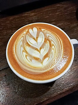 Coffee cup with latte art on the wood table